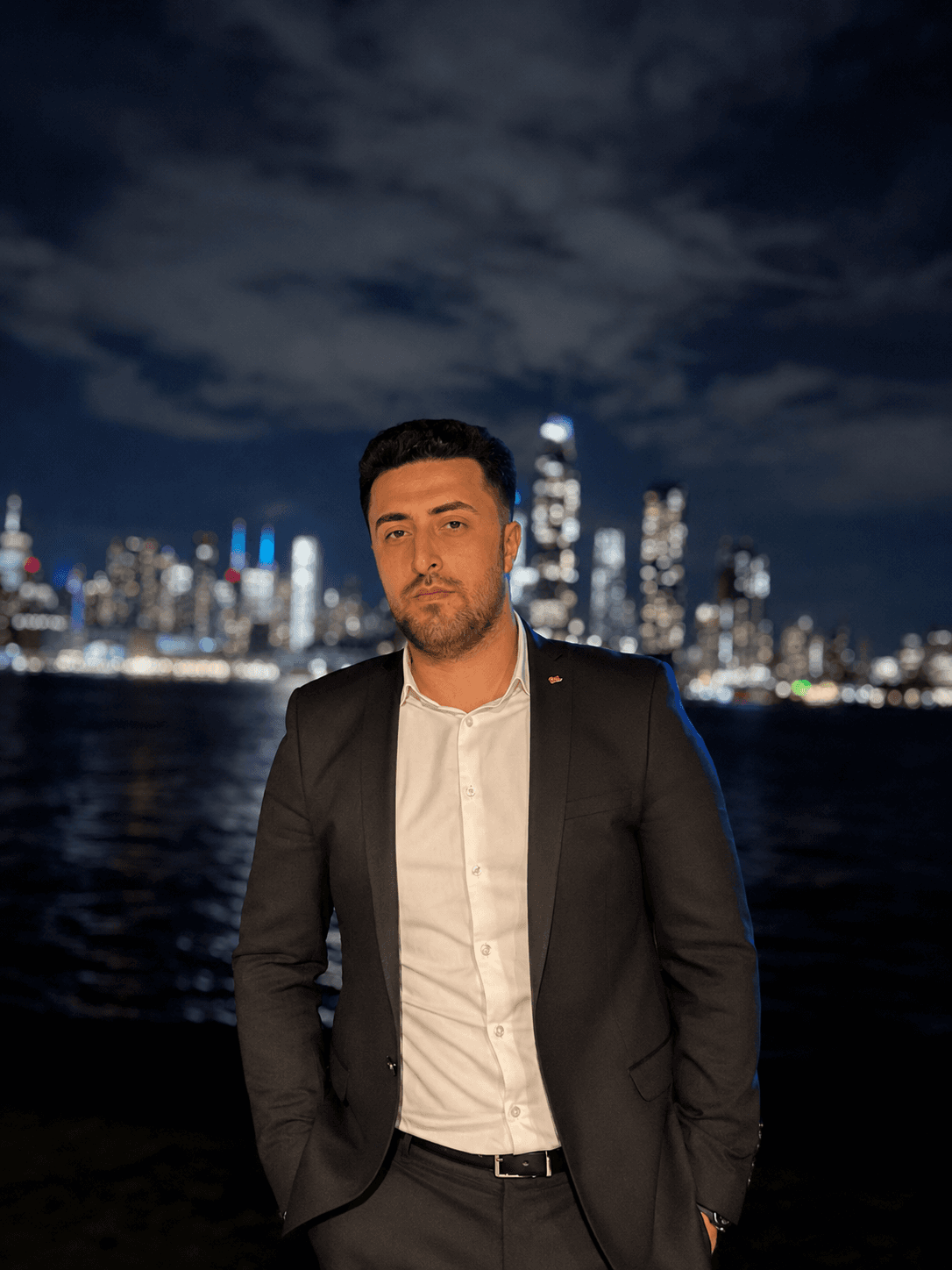 Portrait of Kenan Alim in front of a city skyline at night